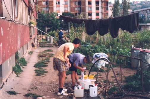 Foto: Ivana Maček. Publicerad i Sarajevo Under Siege: Anthropology in Wartime av Ivana Maček (University of Pennsylvania Press, 2009). ”Washing and filling water containers at the hose that was the only source of water for the entire neighborhood. In the background lawns have been planted with vegetables. Sarajevo suburb of Hrasno, September 1994".